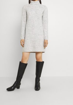Abito a collo alto grigio in maglia con maniche lunghe e lunghezza al ginocchio. Abbinato a stivali neri in pelle alti fino al ginocchio con tacco spesso.