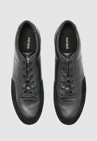 Schwarze Ledersneaker mit Wildlederelementen, Schnürdesign, runde Zehenform und weiße Gummisohle; Markenname in Gold innen aufgedruckt.