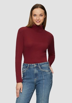 Bordeaux lange mouwen coltrui gemaakt van zacht materiaal, gecombineerd met hoge taille blauwe denim jeans met subtiele slijtplekken en stikseldetails.