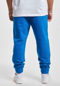Blauwe joggingbroek van zachte stof, met een tapering ontwerp en elastische boorden bij de enkels, gecombineerd met witte sneakers.