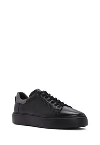 Sneaker in pelle nera con lacci, dalla texture liscia, punta arrotondata e suola in gomma spessa, caratterizzati da cuciture a contrasto e una linguetta sul retro.