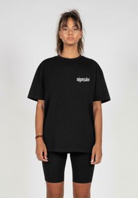 T-shirt nera oversize in cotone, con maniche corte e scollatura rotonda, con testo bianco "mjgonzales" sul lato sinistro del petto.