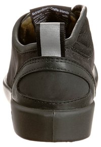 Talons de sneaker noirs avec un tirant réfléchissant, col rembourré, et texte de label intérieur visible indiquant "Extraordinary Crafts blends."