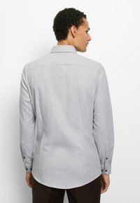 Langärmeliges Hemd in hellgrau mit feinen schwarzen Streifen. Es verfügt über einen klassischen Kragen, geknöpfte Manschetten und einen geraden Saum.