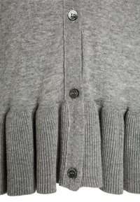 Zbliżenie na szary materiał dzianinowy o pionowej, żeberkowej strukturze i czterema ciemnymi guzikami ustawionymi na centralnej plisie.