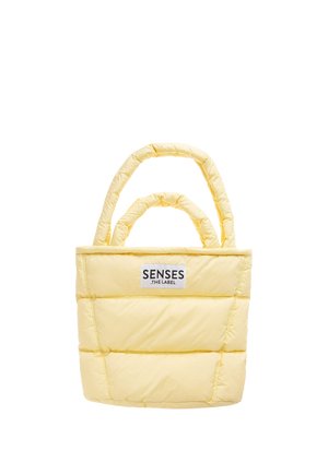 Gepolsterte hellgelbe Tragetasche mit zwei Griffen und einem "SENSES THE LABEL"-Aufnäher vorne mittig vor weißem Hintergrund.