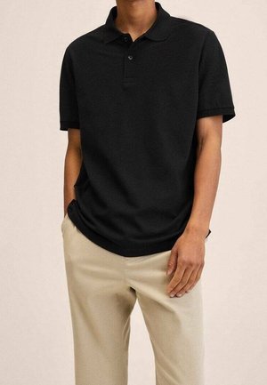 Czarna, krótka koszulka polo z trzema guzikami, wykonana z miękkiego materiału, noszona z jasnobeżowymi spodniami, prezentująca luźny krój.