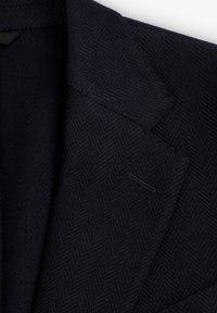 Blazer de espiga azul marino con solapas estructuradas, cuello con muesca y cierre de un solo botón. Presenta una tela texturizada y sutiles detalles de costura.