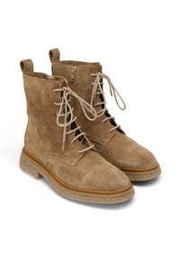 Botas de tobillo de ante marrón con cordones y cremallera lateral. Suela de goma con un acento texturizado beige. Cuenta con dos tiradores en la parte superior.