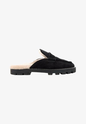 Mocasín de ante negro tipo slip-on con suela de goma gruesa y forro de piel beige dentro y alrededor del área del talón.