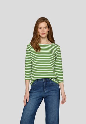 Gestreiftes langärmeliges Shirt in Grün und Weiß mit einem Bootsausschnitt, kombiniert mit dunkelblauen Jeans. Glatte Textur, lockere Passform.