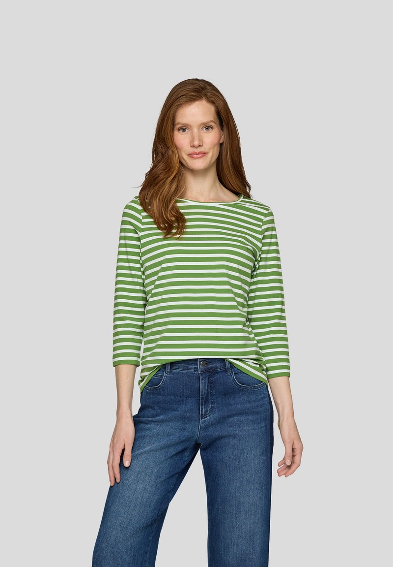 Gestreiftes langärmeliges Shirt in Grün und Weiß mit einem Bootsausschnitt, kombiniert mit dunkelblauen Jeans. Glatte Textur, lockere Passform.