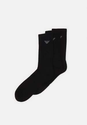 Chaussettes en coton noir avec une texture côtelée, trois paires présentées, avec un petit logo gris sur le dessus pour le branding.