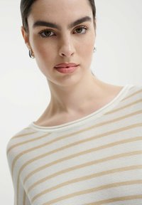 Top a manica larga a righe in tonalità crema e beige, con una ampia scollatura a barca e tessuto testurizzato con sottili accenti a coste.