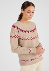 Suéter de punto beige con patrones geométricos en rojo y púrpura alrededor del cuello y las mangas. Presenta un cuello redondo y un ajuste relajado.