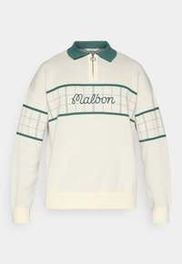 Pull en tricot crème avec accents verts et col. Comprend une fermeture éclair d'un quart, le mot "Malbon" brodé et des motifs en grille sur les manches et le corps.