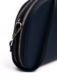 Navy leather bag with silver zippers, featuring textured fabric, rounded shape, and double zipper closure. Smooth finish on one side.