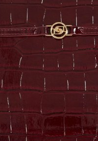 Burgundy faux-crocodile leather handbag with a glossy finish and a gold interlocking logo clasp detail on the front.