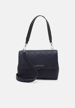 Granatowa torebka Valentino z przeszywanym klapą, złotym logo i dwoma odpinanymi paskami na białym tle.
