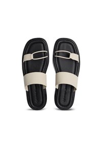 Sandalias tipo slide en negro y beige con correas anchas, plantilla texturizada y una presilla para el dedo de color contrastante. Presentan líneas limpias y un diseño minimalista.