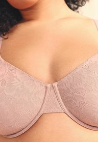 Kanten bh in zacht roze met een V-hals ontwerp. Heeft een bloemenpatroon, gebogen cups en een gladde stoftextuur. Verstelbare bandjes inbegrepen.