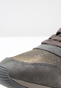 Šedé nubukové tenisky s metalickou zlatou síťovinou, texturovanými tkaničkami a gumovou podrážkou s vroubkovaným vzorem pro lepší přilnavost.