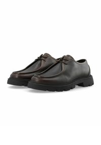 Chaussures en cuir brun avec une finition texturée, à lacets, et semelle épaisse en caoutchouc noir avec un motif de semelle pour une meilleure traction.