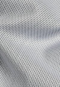 Textile with a white background featuring a repeating black geometric pattern. The fabric has a smooth texture and a slight sheen.