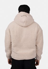 Beige fleece hoodie with a textured surface and a hood. "Crystal Paris" embroidered on the back. No front view or details visible.