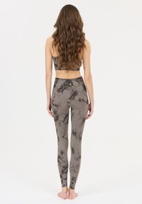 Leggings de patrón de mármol gris con cintura alta y tela elástica, combinados con un top corto a juego, que exhibe una textura suave.