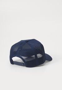 Boné azul-marinho com frente sólida, parte traseira em malha e aba curva. Correia ajustável com logótipo da marca em relevo na lateral.