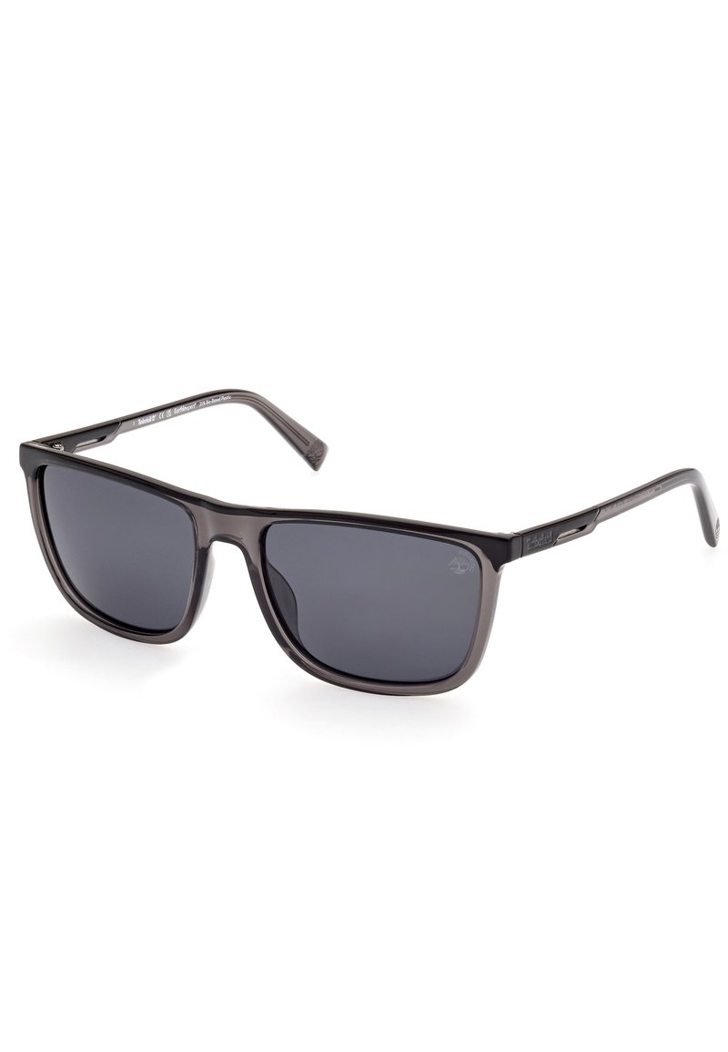 Ochelari de soare din plastic negru cu lentile închise. Cadre de formă pătrată cu margini netede și brațe alungite. Branding subtil pe templu.