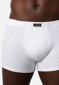 Vita boxershorts med rutmönster, tillverkade av mjukt tyg med en slät textur. Svart varumärkesetikett vid midjan.