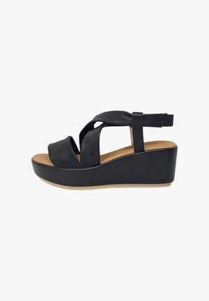 Sandali platform neri con cinturini incrociati, in materiale sintetico, punta aperta e tacco a zeppa curvo. Sottopiedi color sabbia chiaro e trame sottili.