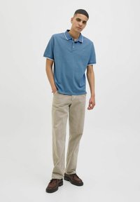 Világoskék rövidujjú poloing, kontrasztos gallérral, bézs kordbársony nadrággal és barna fűzős cipővel párosítva.