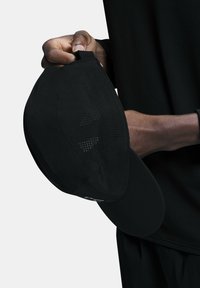 Black cap with a curved brim, made of a smooth fabric. Features mesh ventilation holes and an adjustable strap at the back.