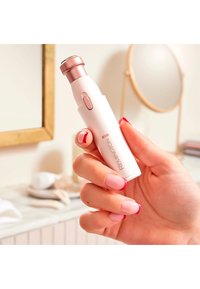 Compact wit groomingtool in het wit met een rosegouden punt en knop. Heeft een ronde kop, vastgehouden in een hand met pink en rode gelakte nagels.