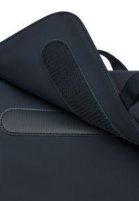 Zwarte tas met een gladde buitenkant, voorzien van een klittenbandsluiting en aanvullende textuurdetail. Inclusief een stevige handgreep.