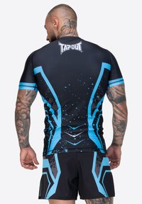 Melna sporta krekls ar ziliem ģeometriskiem rakstiem un akcentiem, izgatavots no elastīga materiāla. Ar īsām piedurknēm un TAPOUT logo uz aizmugures.