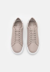 Baskets Calvin Klein, dessus en cuir rose, semelle en caoutchouc blanche, embout circulaire, lacets plats, semelle intérieure rembourrée, design minimaliste avec peu de logo.