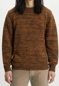 Maglione a fantasia marrone e arancione con polsini e orlo a coste, dotato di un piccolo logo rosso sul petto. Materiale in maglia morbido, design a girocollo.