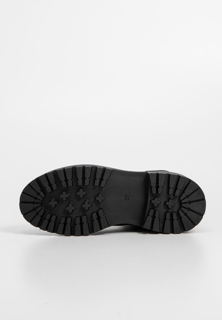 Czarna gumowa podeszwa buta z teksturowanym bieżnikiem i wielokierunkowymi wypustkami, które zapewniają lepszą przyczepność i stabilność. Rozmiar oznaczony jako 37.