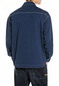 Camicia button-up blu navy con un sottile motivo a griglia, maniche lunghe e cuciture a contrasto. Tessuto in cotone, vestibilità rilassata, dettaglio sulla yoke posteriore.