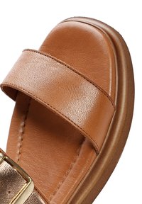 Sandalo in pelle marrone con due ampie cinghie, finitura leggermente texture e un accento metallico. Suola sagomata per comfort e stabilità.