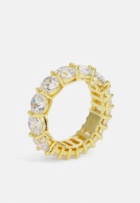 Gullring i gulltone med klare, oval-slepet steiner satt i pronger, som veksler med enkle vertikale akkompagnementer for et strukturert design.