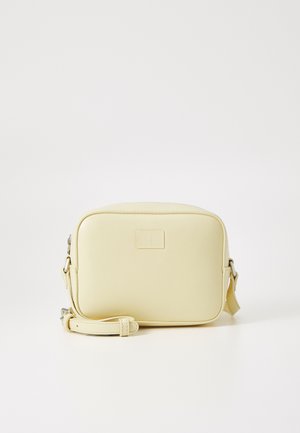 Bolso cruzado rectangular amarillo hecho de cuero sintético suave, con un parche con logotipo en la parte frontal y una correa ajustable.