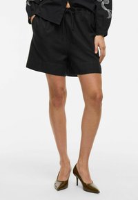 Pantaloni da corsa neri con vita regolabile con cordino, realizzati in tessuto leggero, caratterizzati da una vestibilità ampia e tasche laterali.