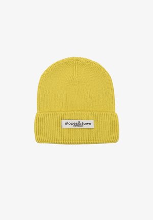 Bonnet en tricot jaune avec une texture côtelée, présentant un revers et une étiquette cousue sur laquelle est inscrit "slopes&town AMSTERDAM".