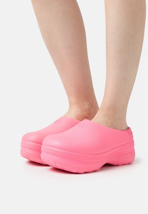 Rosa Gummiclogs mit abgerundeten Zehen und einem erhabenen Logo. Sie haben eine glatte Textur und eine dicke Sohle für Komfort und Langlebigkeit.