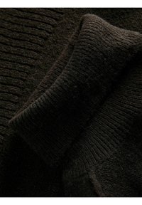 Tessuto di maglione a maglia marrone scuro che mostra una texture a coste nel colletto e nella zona delle spalle, evidenziando la morbidezza e il calore del materiale.